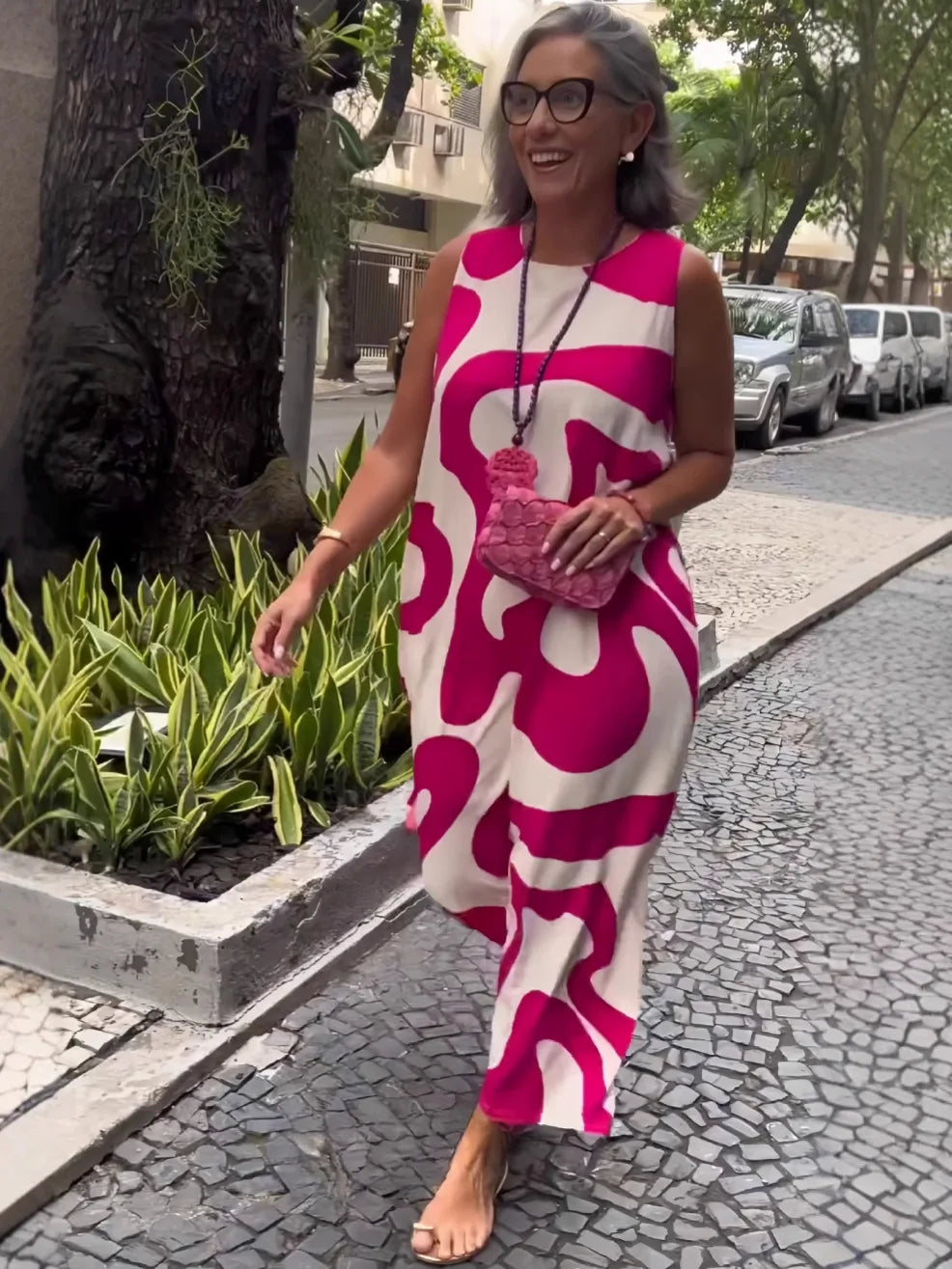 Mulher usando vestido longo rosa com estampa abstrata em ambiente urbano